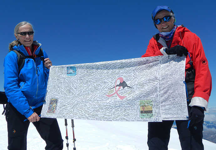 Lynn and Sal stand on top of a mountain. 